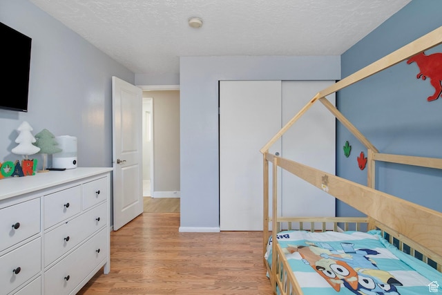 4663 S 2030 W, Taylorsville, UT 84129 - bedroom with light wood-type flooring, a textured ceiling, and a closet