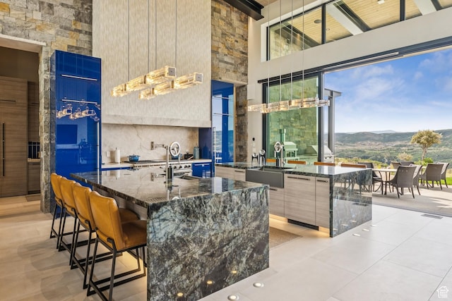 9156 N Sleeping Rock Cir, Kamas, UT 84036 - kitchen featuring modern cabinets, a high ceiling, a mountain view, an island with sink, and dark stone countertops