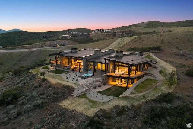 9156 N Sleeping Rock Cir, Kamas, UT 84036 - back of house at dusk with a patio, a chimney, a mountain view, and a metal roof