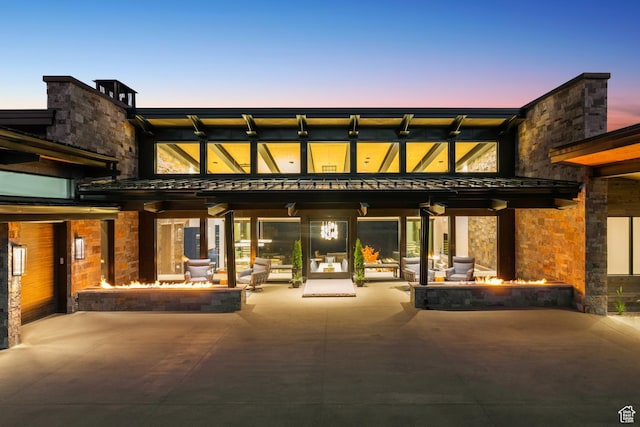 9156 N Sleeping Rock Cir, Kamas, UT 84036 - back of property at dusk with a fire pit, a patio area, and stone siding