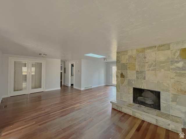2057 E Castle Hill Ave, Cottonwood Heights, UT 84121 - unfurnished living room featuring wood finished floors, a large fireplace, a skylight, and a textured ceiling