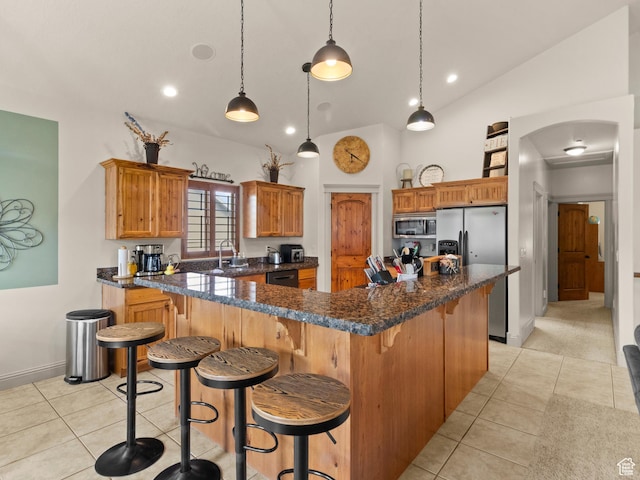 2618 W Mountain Rd, Tremonton, UT 84337 - kitchen with stainless steel appliances, light tile patterned floors, high vaulted ceiling, a breakfast bar area, and brown cabinets