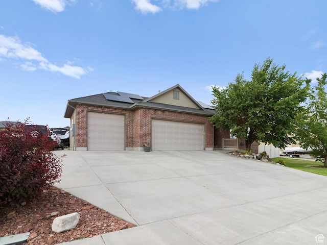 2618 W Mountain Rd, Tremonton, UT 84337 - view of front of property featuring a garage, concrete driveway, solar panels, and brick siding