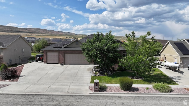 2618 W Mountain Rd, Tremonton, UT 84337 - view of front facade featuring a residential view, concrete driveway, solar panels, a mountain view, and an attached garage