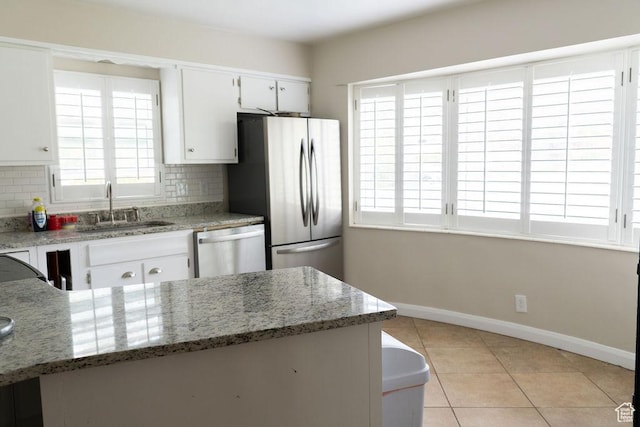 1444 S Beacon Dr E, Salt Lake City, UT 84108 - kitchen featuring appliances with stainless steel finishes, decorative backsplash, light tile patterned flooring, white cabinets, and light stone counters