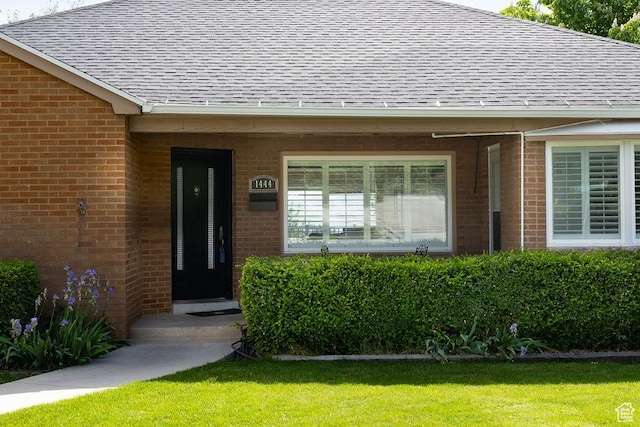 1444 S Beacon Dr E, Salt Lake City, UT 84108 - doorway to property with a shingled roof, brick siding, and a lawn