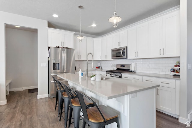 12212 S Sigmon Ln W, Herriman, UT 84096 - kitchen with appliances with stainless steel finishes, a breakfast bar, dark wood-style flooring, backsplash, and light countertops