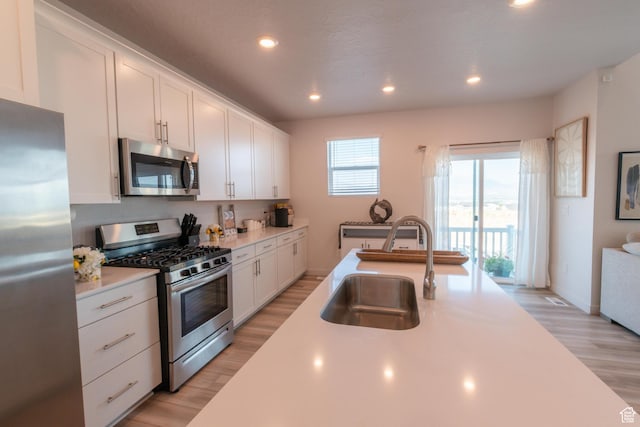 2006 N Red Yearling Dr, Saratoga Springs, UT 84045 - kitchen with stainless steel appliances, light countertops, light wood-type flooring, white cabinetry, and recessed lighting
