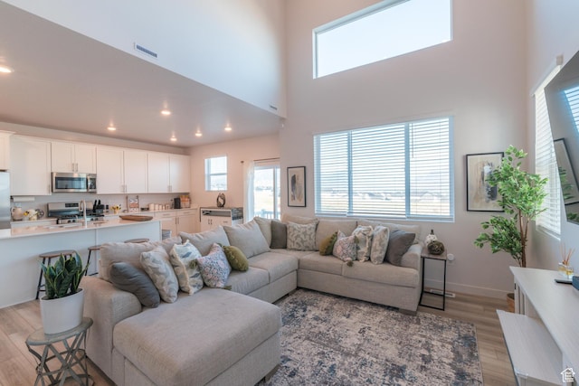 2006 N Red Yearling Dr, Saratoga Springs, UT 84045 - living area featuring light wood-type flooring, a towering ceiling, and recessed lighting