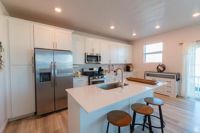 2006 N Red Yearling Dr, Saratoga Springs, UT 84045 - kitchen with stainless steel appliances, light wood-type flooring, white cabinets, a kitchen breakfast bar, and recessed lighting