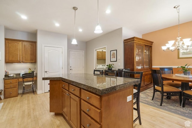 4470 S Snowmass Ct, Millcreek, UT 84124 - kitchen featuring a breakfast bar area, light wood finished floors, a center island, brown cabinets, and a chandelier