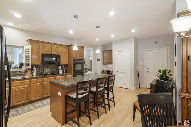 4470 S Snowmass Ct, Millcreek, UT 84124 - kitchen with black appliances, a center island, light wood-style flooring, dark countertops, and recessed lighting