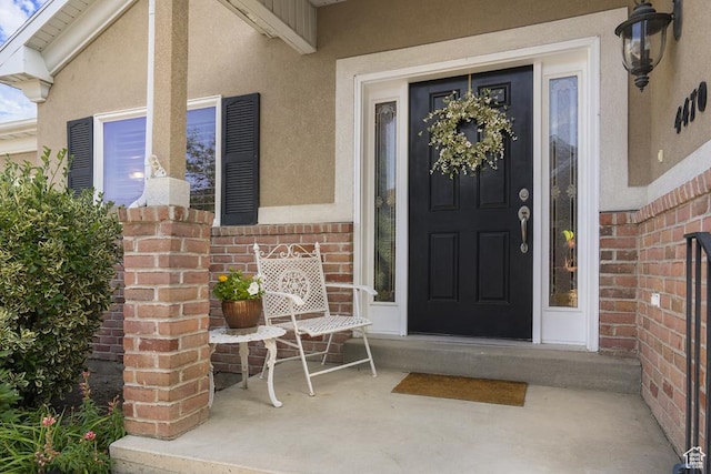 4470 S Snowmass Ct, Millcreek, UT 84124 - doorway to property featuring stucco siding, brick siding, and a porch