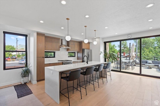 537 S 500 E Unit 106, Salt Lake City, UT 84102 - kitchen with stainless steel appliances, wall chimney exhaust hood, modern cabinets, light countertops, and light wood-style flooring