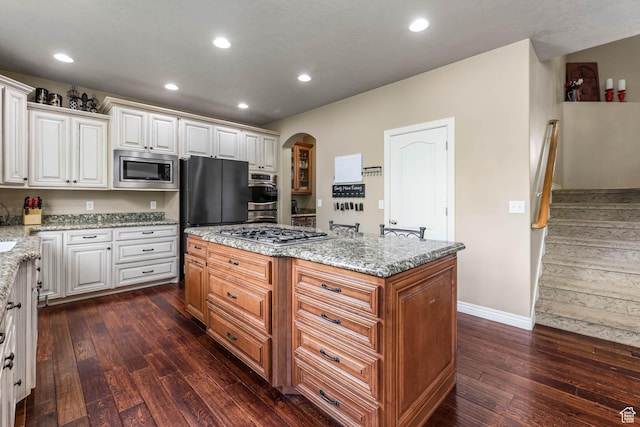 14346 S Fort Duchesne Cv, Herriman, UT 84096 - kitchen with appliances with stainless steel finishes, dark wood-type flooring, arched walkways, a center island, and recessed lighting
