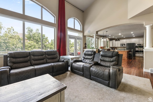 14346 S Fort Duchesne Cv, Herriman, UT 84096 - living area featuring decorative columns, dark wood finished floors, and a towering ceiling