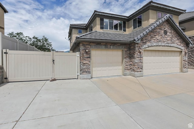 14346 S Fort Duchesne Cv, Herriman, UT 84096 - view of side of home featuring stone siding, a gate, concrete driveway, stucco siding, and an attached garage