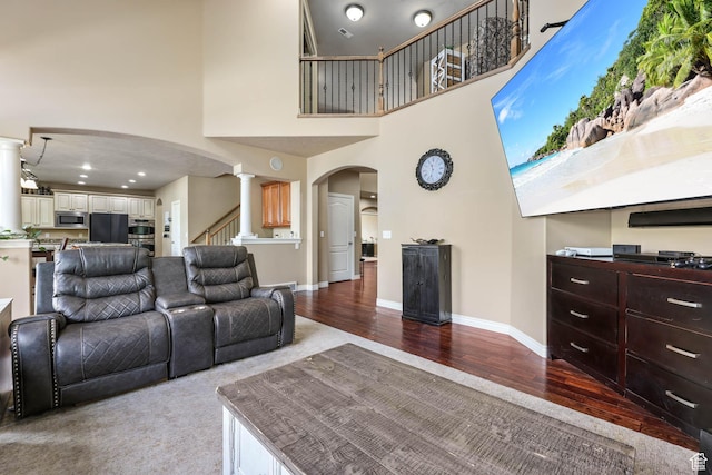 14346 S Fort Duchesne Cv, Herriman, UT 84096 - living room with arched walkways, a towering ceiling, wood finished floors, stairway, and ornate columns
