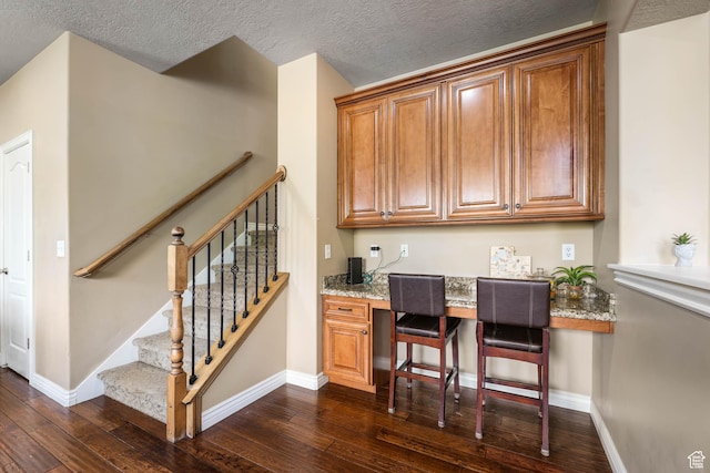 14346 S Fort Duchesne Cv, Herriman, UT 84096 - bar featuring dark wood-type flooring, a textured ceiling, stairway, and built in study area