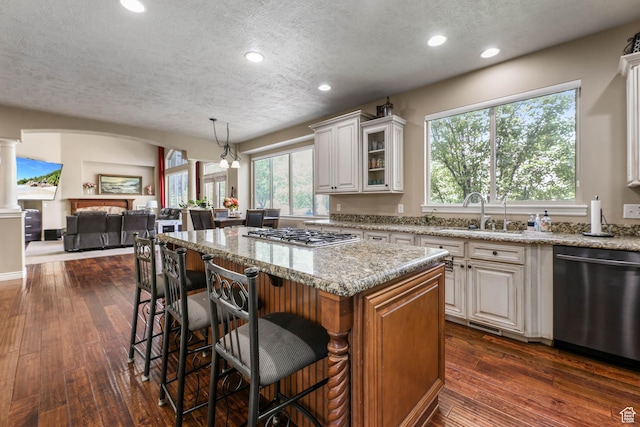 14346 S Fort Duchesne Cv, Herriman, UT 84096 - kitchen featuring stainless steel appliances, a textured ceiling, light stone countertops, glass insert cabinets, and a breakfast bar