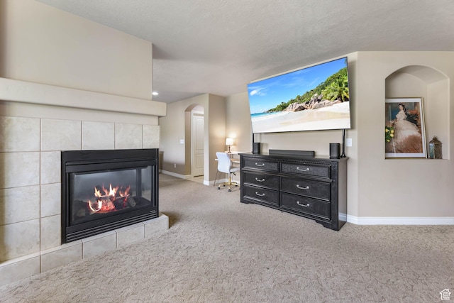 14346 S Fort Duchesne Cv, Herriman, UT 84096 - living room with carpet flooring, a tiled fireplace, arched walkways, and a textured ceiling