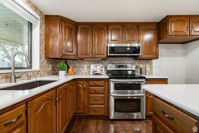 1241 N 575 W, Centerville, UT 84014 - kitchen featuring appliances with stainless steel finishes, brown cabinets, light countertops, dark wood finished floors, and tasteful backsplash