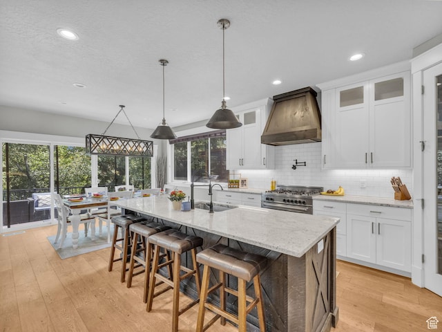 485 Parkview Dr, Summit Park, UT 84098 - kitchen with custom range hood, stainless steel stove, light wood-type flooring, tasteful backsplash, and white cabinetry