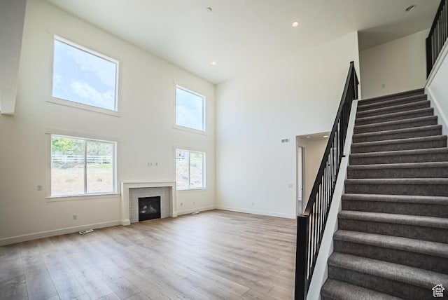 7169 W Moorepark Pl, West Jordan, UT 84081 - unfurnished living room with stairs, a towering ceiling, light wood-style floors, a fireplace, and recessed lighting
