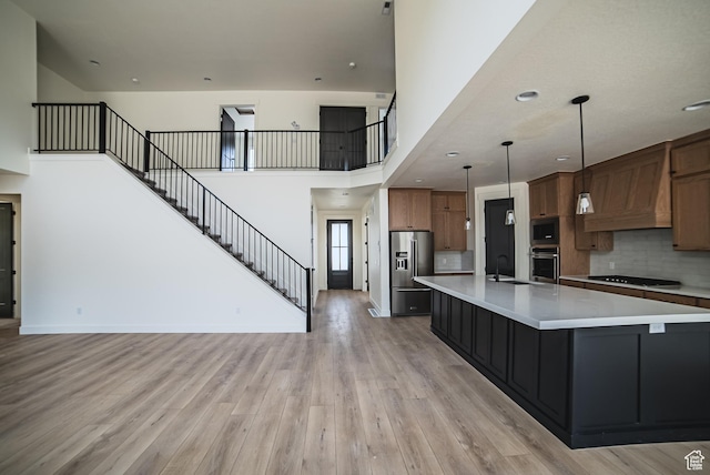 7169 W Moorepark Pl, West Jordan, UT 84081 - kitchen with appliances with stainless steel finishes, light countertops, light wood-style floors, open floor plan, and custom range hood