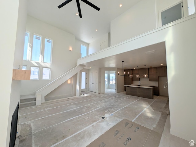 7083 W Granbury Dr S Unit 256, South Jordan, UT 84009 - unfurnished living room featuring a towering ceiling, stairway, ceiling fan, a chandelier, and recessed lighting