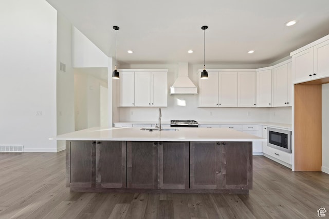 6941 W Farnsworth Peak Dr S Unit 316, West Jordan, UT 84081 - kitchen with custom exhaust hood, built in microwave, light wood-type flooring, light countertops, and recessed lighting