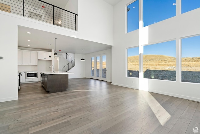 6941 W Farnsworth Peak Dr S Unit 316, West Jordan, UT 84081 - unfurnished living room featuring a high ceiling, light wood-style flooring, stairway, and recessed lighting