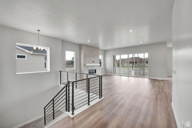 6199 W Wapiti Ridge Ln Unit 333, Herriman, UT 84096 - spare room featuring wood finished floors, a textured ceiling, a large fireplace, a chandelier, and recessed lighting