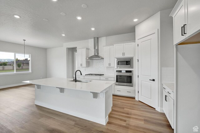 6199 W Wapiti Ridge Ln Unit 333, Herriman, UT 84096 - kitchen featuring appliances with stainless steel finishes, wall chimney range hood, backsplash, light wood-style flooring, and recessed lighting