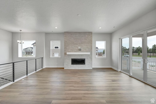 6199 W Wapiti Ridge Ln Unit 333, Herriman, UT 84096 - unfurnished living room featuring wood finished floors, a chandelier, a textured ceiling, recessed lighting, and a fireplace