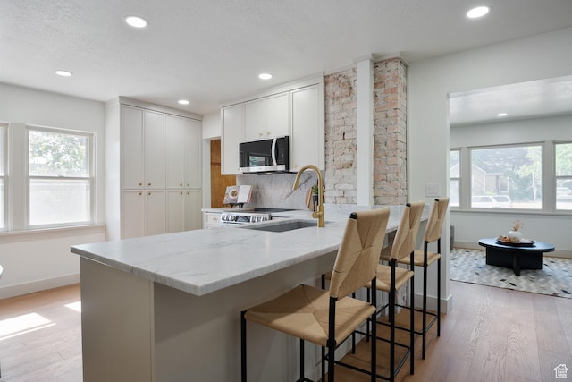 1214 E Parkway Ave, Salt Lake City, UT 84106 - kitchen with stainless steel microwave, light stone counters, plenty of natural light, recessed lighting, and light wood-style floors