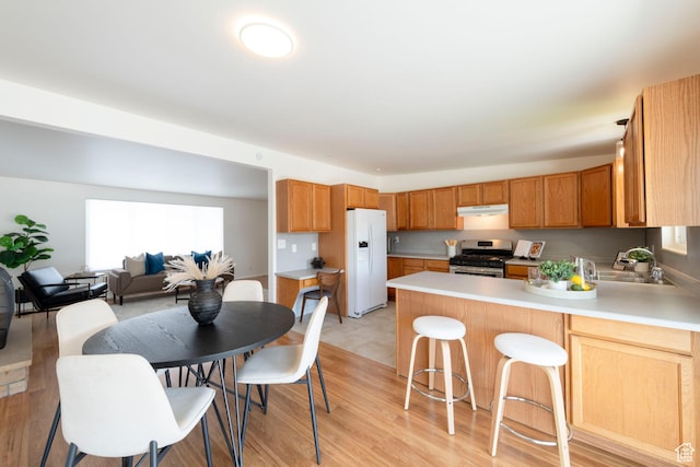 2260 E Murray Holladay Rd S Unit 22, Holladay, UT 84117 - kitchen with white refrigerator with ice dispenser, stainless steel gas stove, under cabinet range hood, a peninsula, and light countertops