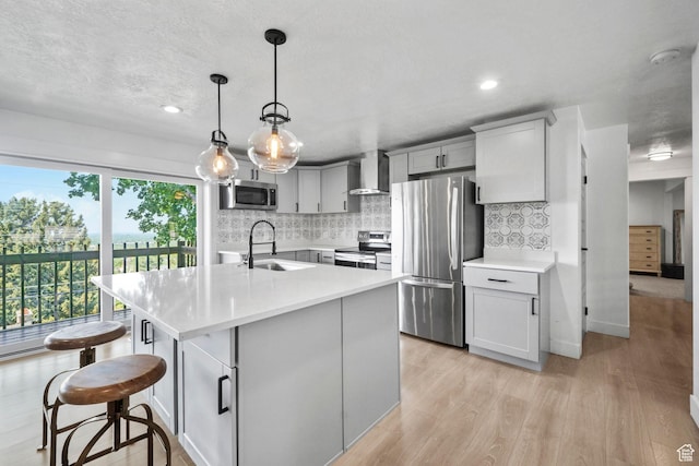 2451 E Cavalier Dr, Cottonwood Heights, UT 84121 - kitchen with stainless steel appliances, light countertops, backsplash, light wood-style floors, and wall chimney range hood