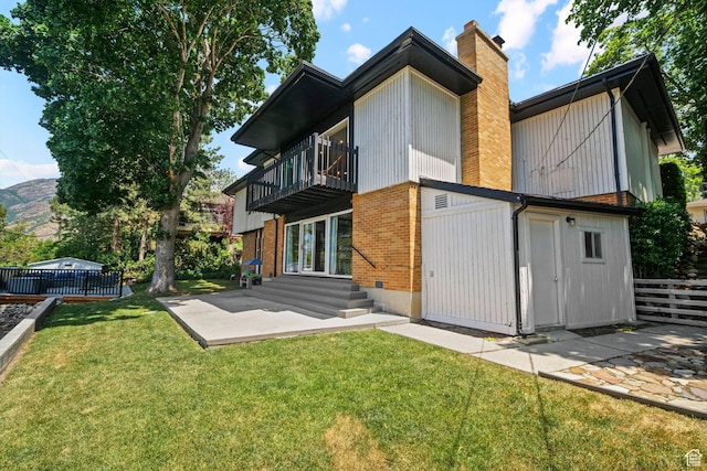2451 E Cavalier Dr, Cottonwood Heights, UT 84121 - back of property with a balcony, a chimney, brick siding, a patio area, and entry steps