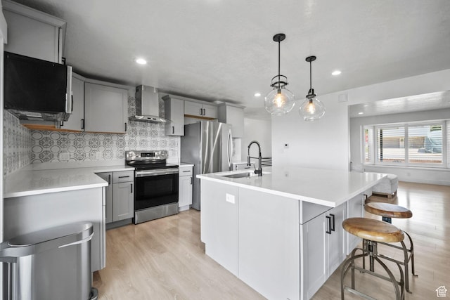 2451 E Cavalier Dr, Cottonwood Heights, UT 84121 - kitchen featuring stainless steel appliances, wall chimney exhaust hood, gray cabinets, light wood-style floors, and light countertops
