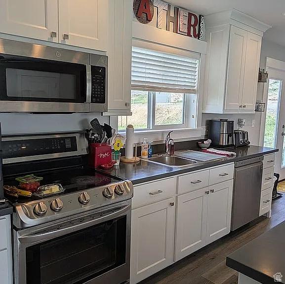 81 S T St, Eureka, UT 84628 - kitchen with stainless steel appliances, dark wood finished floors, white cabinets, and dark countertops