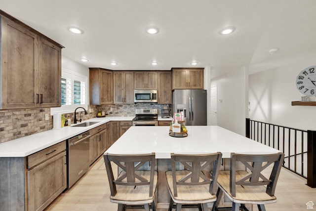 8322 S Copper Vista Cir, West Jordan, UT 84081 - kitchen with appliances with stainless steel finishes, light wood-style flooring, a kitchen bar, tasteful backsplash, and recessed lighting