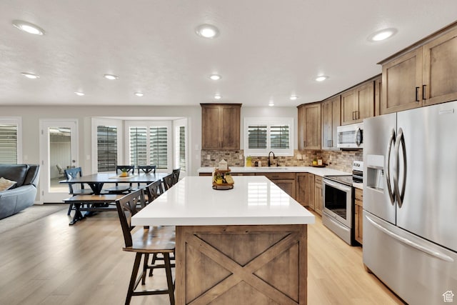 8322 S Copper Vista Cir, West Jordan, UT 84081 - kitchen with appliances with stainless steel finishes, light wood-type flooring, recessed lighting, a kitchen island, and backsplash