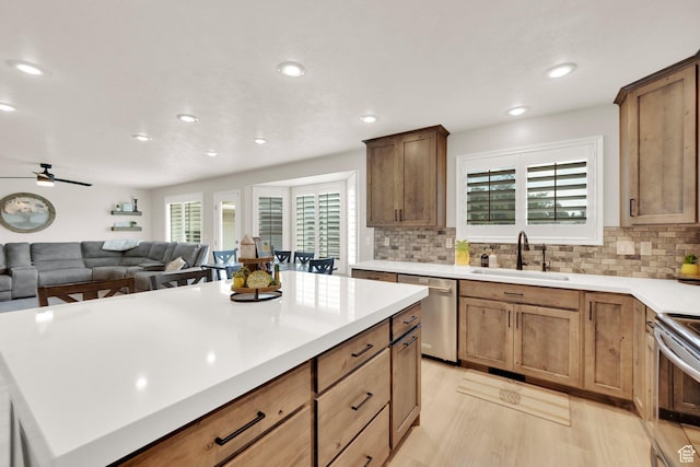 8322 S Copper Vista Cir, West Jordan, UT 84081 - kitchen featuring appliances with stainless steel finishes, light wood-style flooring, backsplash, ceiling fan, and a center island