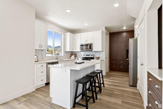 579 E Kings Lndg, Tooele, UT 84074 - kitchen with appliances with stainless steel finishes, a breakfast bar area, backsplash, white cabinetry, and recessed lighting