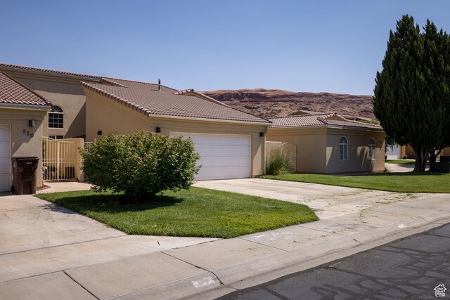 542 W Hale Ave, Moab, UT 84532 - view of front of property with driveway, stucco siding, a garage, a front yard, and a mountain view