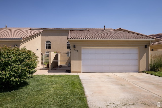 542 W Hale Ave, Moab, UT 84532 - mediterranean / spanish house with stucco siding, concrete driveway, a gate, an attached garage, and a tiled roof