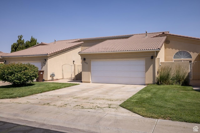 542 W Hale Ave, Moab, UT 84532 - mediterranean / spanish home with stucco siding, a garage, driveway, a tiled roof, and a front yard