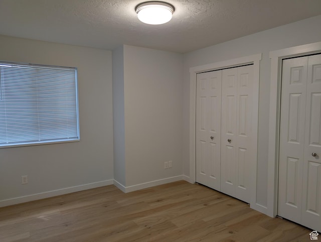 623 S 500 W Unit 17, Provo, UT 84601 - unfurnished bedroom with light wood-style floors, a textured ceiling, and multiple closets