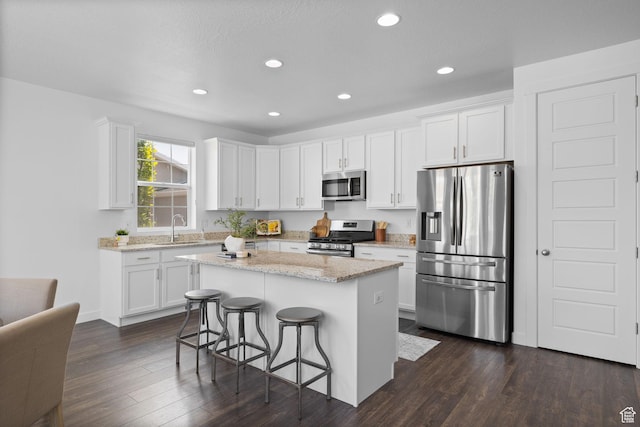 6856 W 8060 S, West Jordan, UT 84081 - kitchen featuring stainless steel appliances, white cabinets, a breakfast bar, dark wood-type flooring, and recessed lighting